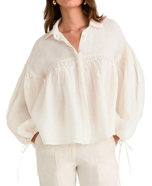 Woman in a Merlette New York Azurea Top with balloon sleeves and button details.