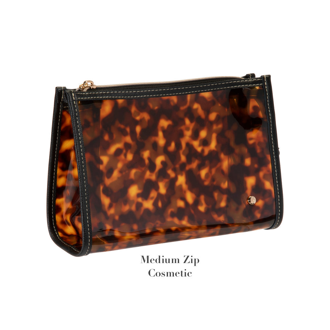A medium-sized cosmetic bag from the Miami Tortoise Travel Collection by Stephanie Johnson, featuring a tortoiseshell pattern and faux-leather trim. Shown against a white background with "Medium Zip Cosmetic" below. Ideal for organizing travel essentials.