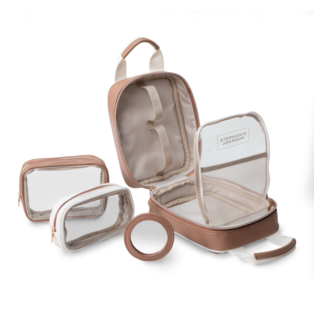 The Marbella Mocha Travel Collection by Stephanie Johnson is displayed open, revealing interior pockets. Three matching transparent cosmetic pouches and a circular accessory are arranged beside this versatile makeup bag.