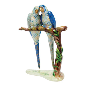 The Herend Reserve Collection Pair of Macaws is a limited edition porcelain figurine featuring two blue and white parrots perched together on a leafy branch, set on a white base.