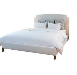 The Laguna Cloud Cut Corner King Bed by Lee Industries features a modern white frame upholstered in luxurious Laguna Cloud fabric, topped with white bedding and four patterned accent pillows for contemporary elegance, shown on a white background.