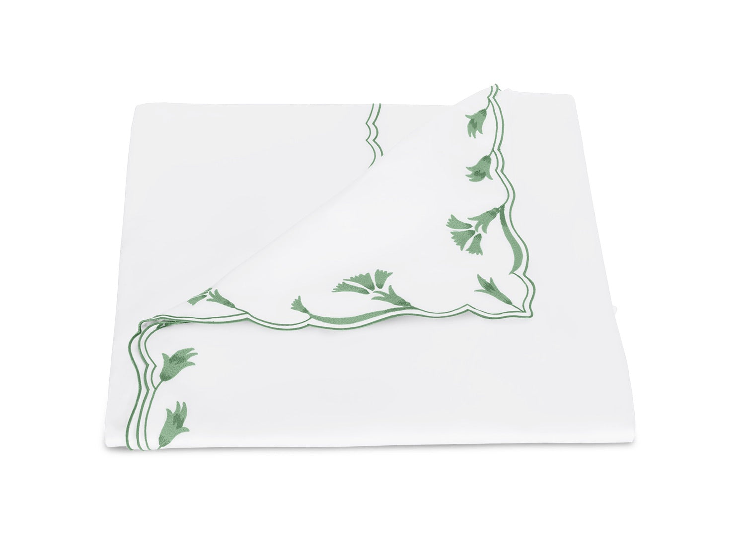 Beautifully folded white napkin from the Marcella Bedding Collection by Matouk, featuring green scalloped floral embroidery along the edges and partially flipped to reveal the elegant design on both sides.
