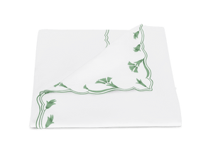 A neatly folded napkin from the Matouk Marcella Bedding Collection in Clover, featuring green scalloped florals and delicate embroidery, is displayed on a plain white background.