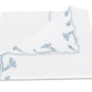A folded white napkin from the Matouk Marcella Bedding Collection, featuring a blue scalloped floral border along two edges reminiscent of embroidered bedding, displayed on a white background.