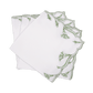 A set of four Marcella Napkins by Matouk, featuring white fabric with green embroidered leaf motifs and scalloped edges, displayed fanned out on a white background.