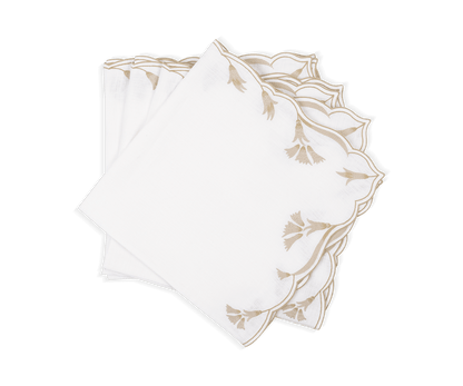 The Marcella Napkin Set by Matouk features three white cloth napkins with scalloped edges and beige embroidered leaf patterns, neatly stacked on a white background.