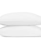Two white pillows from the Marcella Bedding Collection by Matouk are stacked horizontally, each featuring a green leaf embroidered detail on the corners, set against a plain white background.