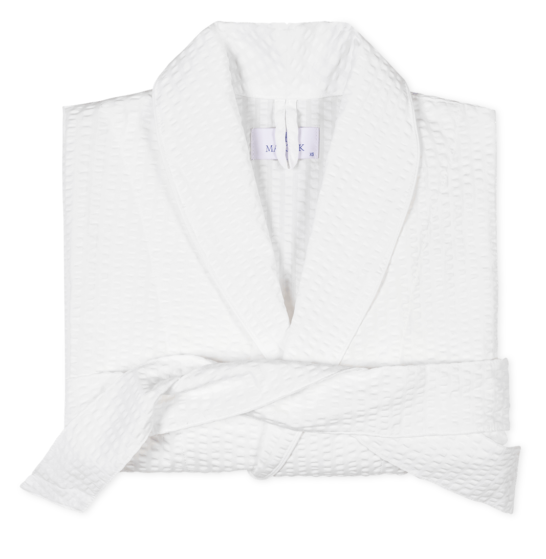 The Matteo White Robe by Matouk, featuring a lightweight waffle weave, shawl collar, and matching belt, is neatly folded on a plain background.