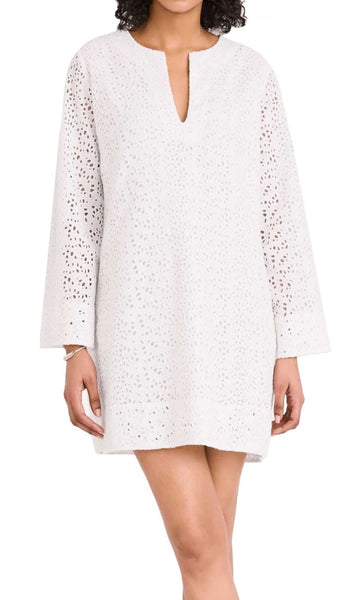 Woman in a Merlette New York white cotton eyelet dress with a v-neckline and perforated bell sleeves.