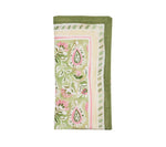 The Mira Napkin Set by Kim Seybert features folded linen napkins with a hand-painted green, pink, and white floral and paisley pattern, finished with striped borders.