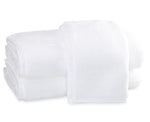 Two neatly folded white towels from the Matouk Milagro Bath Collection, crafted with zero-twist yarns, are stacked on a plain white background.
