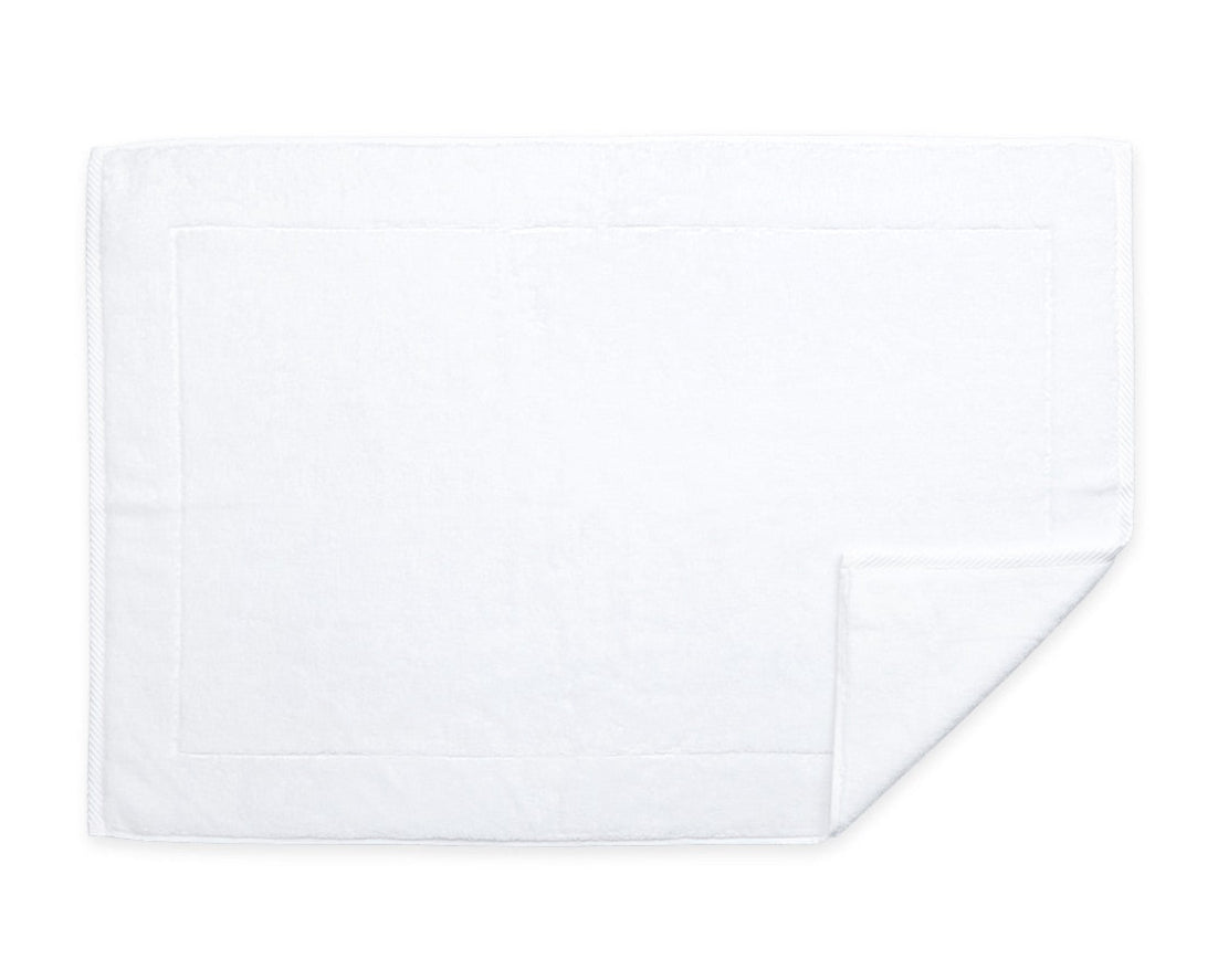 A neatly folded white rectangular towel from the Matouk Milagro Bath Collection, made from zero-twist yarns with one corner turned up, shown on a white background.