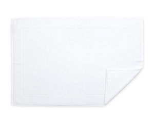 The Matouk Milagro Bath Collection features a square white luxury cotton cloth with a folded corner and simple border design on a plain background.