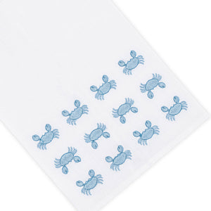 The Haute Home Mini Crab Bath Collection in Blue features a white Italian linen napkin with small blue hand embroidered crabs arranged in rows near one corner.