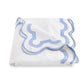 A folded white blanket from the Matouk Mirasol Bedding Collection, featuring decorative light blue trim and scalloped edges, crafted from luxurious 600 thread count Egyptian cotton percale, displayed on a plain white background.