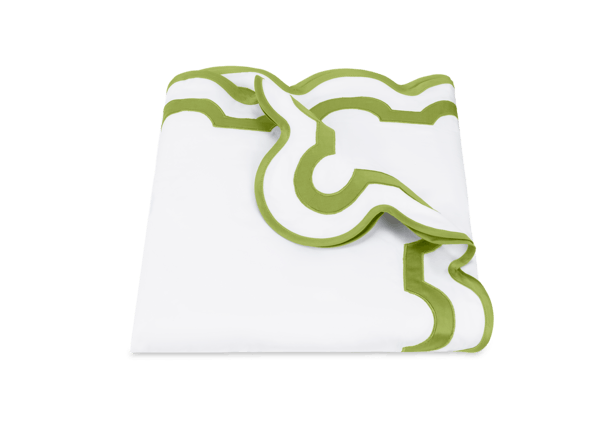 A neatly folded white napkin with a decorative green border and scalloped edge, crafted from luxurious Egyptian cotton percale inspired by the Matouk Mirasol Bedding Collection in Grass.