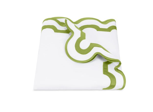 Folded white cloth with green geometric trim along the edges, partially unfolded to display the decorative border design—crafted from luxurious Egyptian cotton percale with a 600 thread count, the Mirasol Bedding Collection by Matouk is made in Italy for exceptional quality.