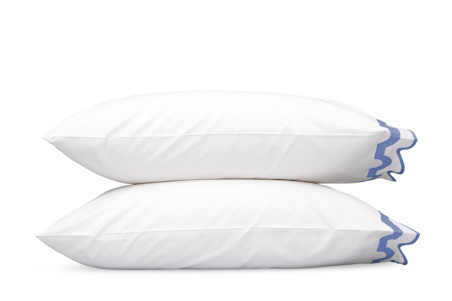 Two white pillows with blue decorative trim from the Matouk Mirasol Bedding Collection, expertly crafted from luxurious 600 thread count Egyptian cotton percale, are stacked on top of each other against a plain white background.