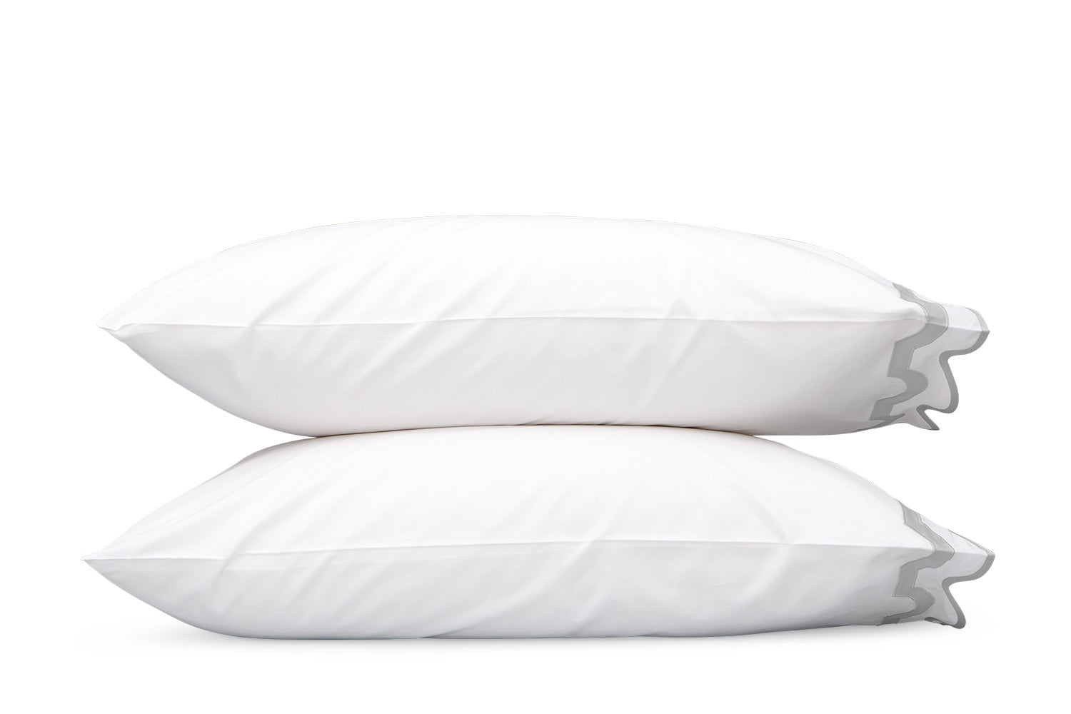 Two white pillows with grey piping from the Matouk Mirasol Bedding Collection, crafted from luxurious Egyptian cotton percale, are stacked on top of each other against a plain white background.