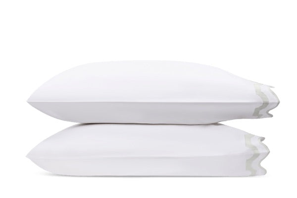 Two white pillows from the Matouk Mirasol Bedding Collection stacked horizontally, showcasing subtle decorative stitching on the right side. Crafted in Italy from luxurious Egyptian cotton percale with a 600 thread count, these pillows are set against a plain white background, exemplifying superior comfort and elegance.