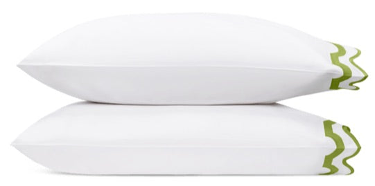 Two pillows from the Mirasol Bedding Collection by Matouk, crafted from luxurious white Egyptian cotton percale with a 600 thread count, are stacked atop one another. Each pillow features a distinctive green decorative trim on one end, set against a crisp white background.