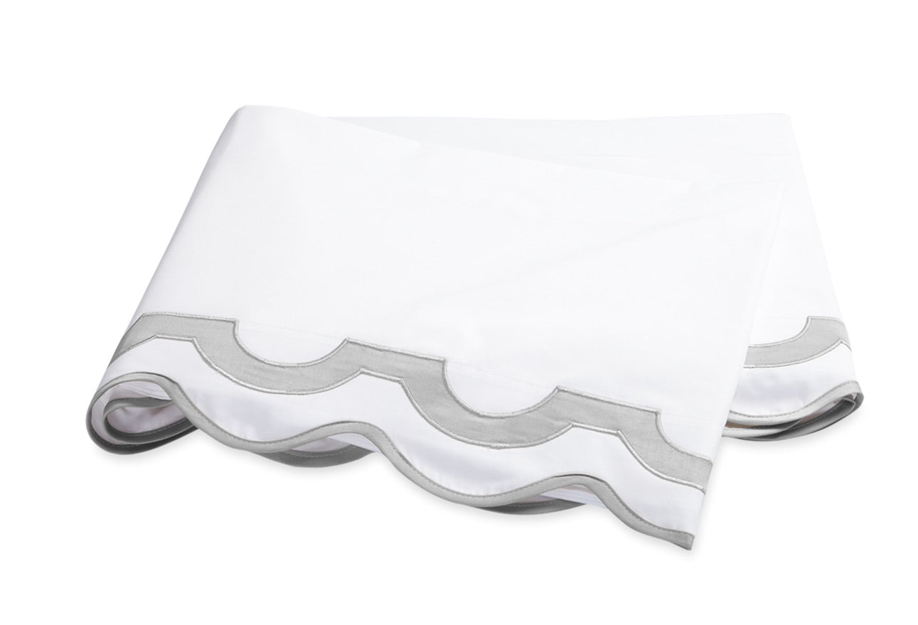 A crisp white sheet from the Matouk Mirasol Bedding Collection, featuring scalloped edges and light gray trim, beautifully crafted from luxurious Egyptian cotton percale and shown against a plain white background.