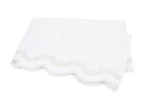 A folded white towel with scalloped edges and a light gray trim, from the Matouk Mirasol Bedding Collection, crafted from luxurious 600 thread count Egyptian cotton percale, placed on a plain white background.