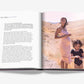 Open book from Assouline, "Mother and Child": a pregnant woman in a light pink dress stands in a dry grassy field with a child in black. Text by Claiborne Swanson Frank is featured on the left page.