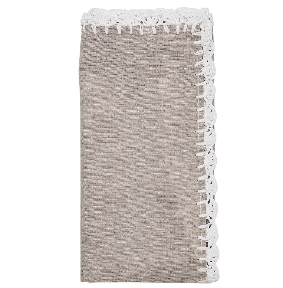 The Shell Edge Napkin Set by Kim Seybert features folded beige linen napkins with white lace trim, perfect for bohemian table settings and displayed against a white background.