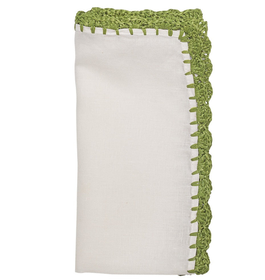 The Shell Edge Napkin Set by Kim Seybert features folded white linen napkins with a green crocheted border, ideal for bohemian table settings.