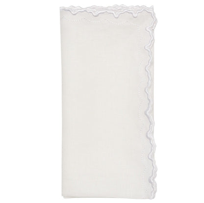 The Arches Napkin Set by Kim Seybert features folded white linen napkins with a geometric design and a scalloped, embroidered edge on one side, shown against a plain white background.