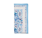 The Mira Napkin Set by Kim Seybert features folded light blue and white linen napkins with a hand-painted paisley pattern, delicate leaf accents, and a striped border.