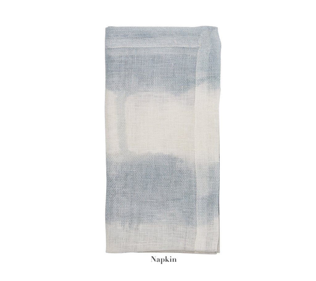 A folded napkin from the Kim Seybert Watercolor Stripe White/Blue Linen Collection, featuring a subtle blue and white gradient, is displayed on a white background. "Napkin" is printed below.