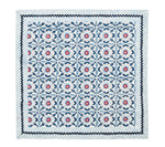 The Majorelle Napkin Set by Kim Seybert is a square, handcrafted textile featuring Indian block-printed geometric and floral motifs in blue, red, and white, finished with bold zigzag and stripe borders.