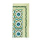 The Kim Seybert Majorelle Napkin Set features a folded napkin with green, blue, and white floral and leaf patterns, a striped border, and green rickrack trim, inspired by Indian block printing for an artisanal feel.