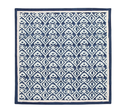 The Alfresco Napkin Set by Kim Seybert features a dark blue and white geometric pattern inspired by block printing, with repeating diamond shapes, stylized floral designs, and a solid blue border.