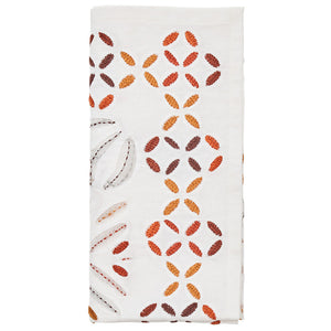 The Kim Seybert Malta Napkin Set features white napkins with embroidered red, orange, and brown leaf patterns and cutwork-inspired cut-out details along one side.