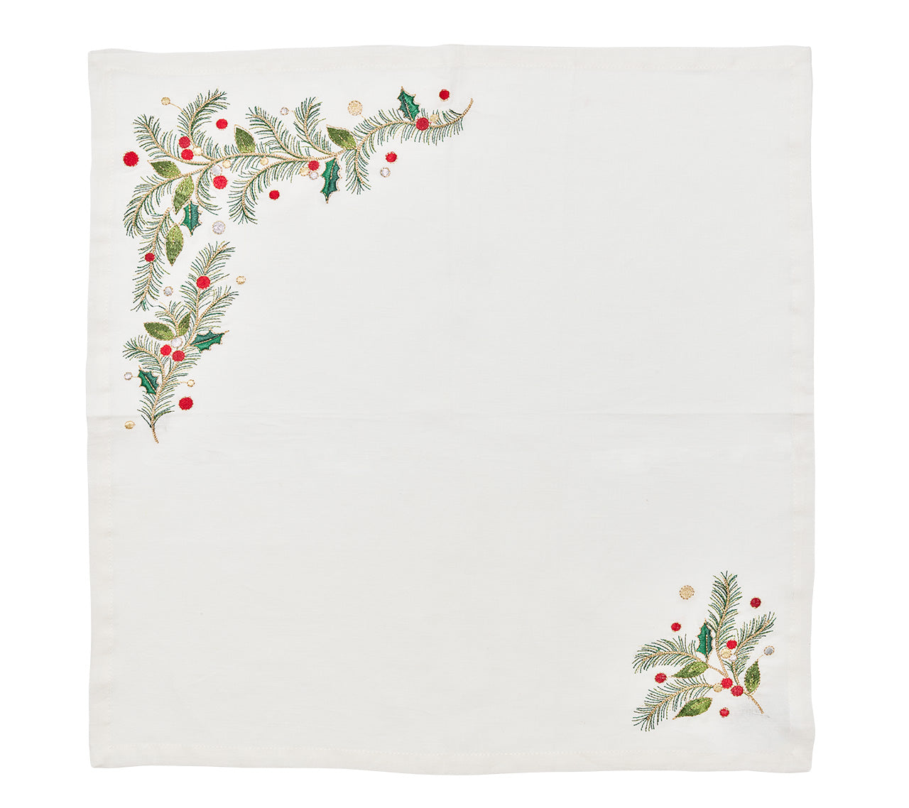 The Christmas Carol Table Linen Collection by Kim Seybert features a white cloth napkin embroidered with green pine branches and red-gold berries in two corners, ideal for festive holiday table settings.