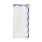 The Lune Napkin Set by Kim Seybert features folded white napkins with scalloped edges and blue stitching, perfect for elevating any table setting.