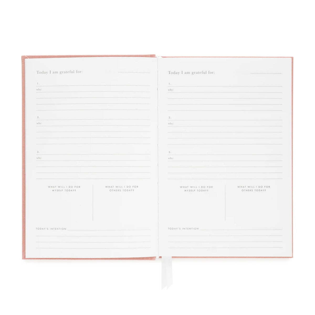 An open Flax Gratitude Journal by Sugar Paper displays two pages with prompts for gratitude, intentions, and daily actions, featuring lined sections for writing. This journal includes a daily check-in and is finished with a pink cover and white ribbon bookmark.