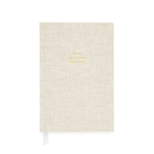 The Flax Gratitude Journal by Sugar Paper is a beige linen-covered journal with elegant gold “Daily Gratitude Journal” text, featuring thoughtful prompts and a white ribbon bookmark to guide your daily reflections.