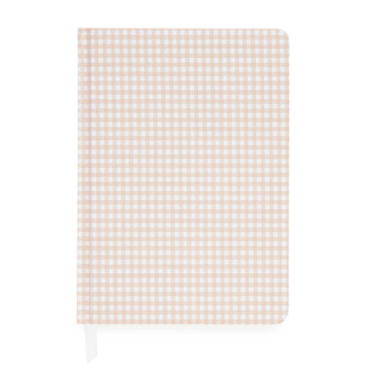 The Pink Gingham Tailored Journal by Sugar Paper features a charming beige and white gingham check cover. Shown closed with a white ribbon bookmark peeking out from the bottom left, this journal offers a durable book cloth hardcover and lined pages for organized note-taking.
