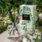 The Nest Indian Jasmine Decorative Reed Diffuser stands next to its floral box on a stone surface, surrounded by white jasmine blooms and filled with premium fragrance oils.