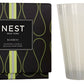 Two products from Nest: on the left, a decorative box featuring a NEST Bamboo Votive Candle, and on the right, a transparent glass candle holder with the brand's logo.