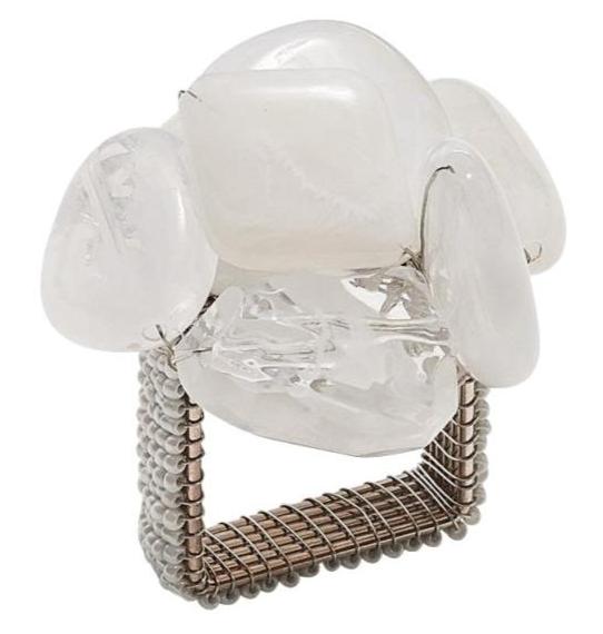 The Kim Seybert Sea Stone Napkin Ring features a silver wire design with a large clear stone and three small white stones, inspired by beach stones—an ideal, unique accent for coastal-themed table settings.