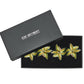 A black Kim Seybert box, lid ajar, displays a set of four Palm Coast Napkin Rings—nature-inspired table decor in green, gold, and brown.