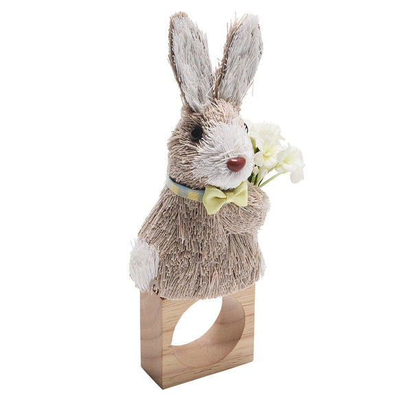 The Kim Seybert Easter Bunny Napkin Ring showcases a bunny with a yellow bow tie holding white flowers on a wooden ring base, perfect for adding festive charm.