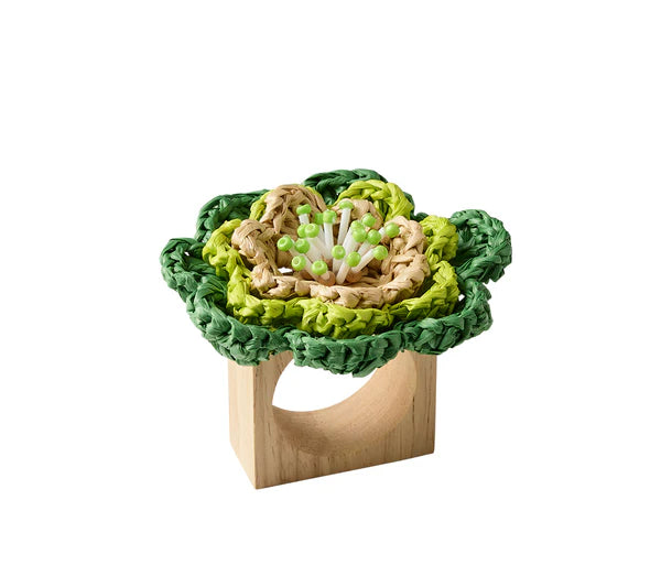 The Kim Seybert Pareo Napkin Ring features a decorative green and beige raffia-style flower made from woven material attached to a wooden ring.