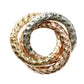The Kim Seybert Trinity Napkin Ring Set features three interlocking hand-hammered metal rings in gold, rose gold, and silver tones, creating an elegant and modern accent for any table setting.