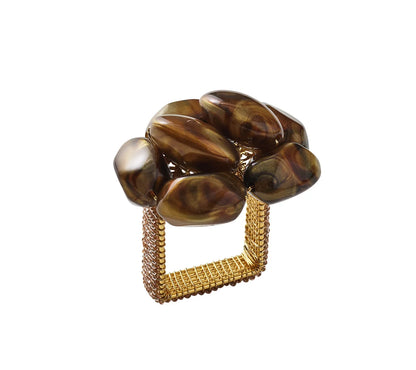 Kim Seybert’s Bonton Napkin Ring features a gold-tone square band adorned with a cluster of polished brown stones, evoking the elegance of luxurious napkin rings set atop crisp white linen.